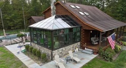Indoor swimming pool enclosed by large glass windows, providing a panoramic view of a lush grassy field and a small shed outside